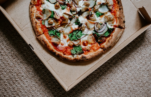 a pizza in a box with cheese and spinach. Learn more about food addiction and gluttony.