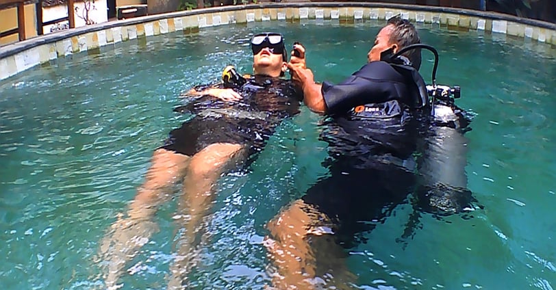 a man and woman in scuba gear in a pool for rescues dive course