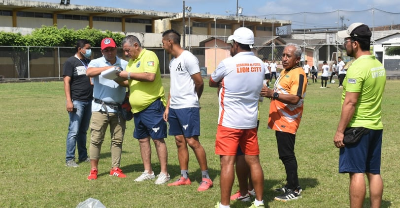 a group of people standing around a soccer field