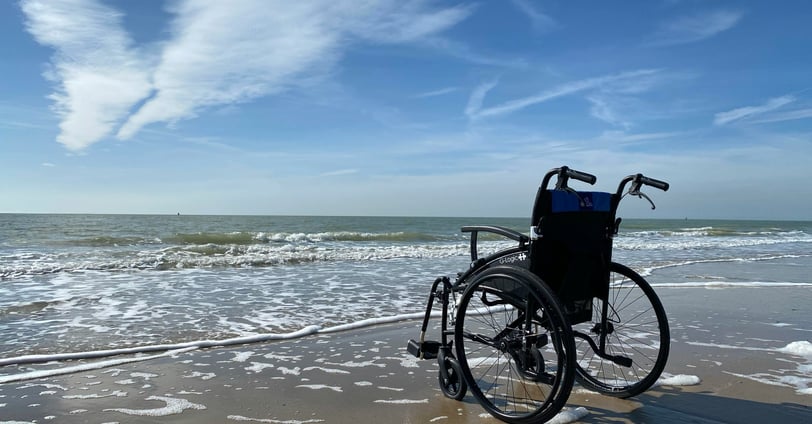 Wheelchair at edge of water on beach. Photo credit - Photo by //unsplash.com/@hansmoe