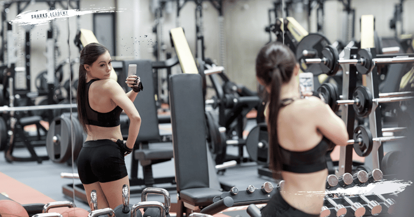 Joven en gimnasio tomándose selfies, reflejo del problema del fitness sin propósito