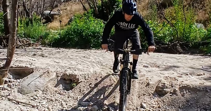 Mountain biker riding through deep sand with steady speed and balance.