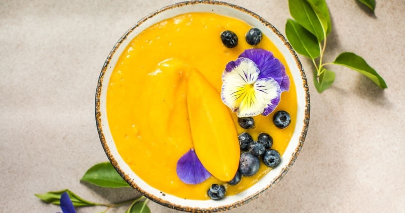 a bowl of african mango and flowers on a table