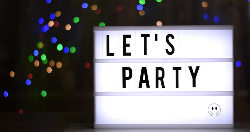 a lit sign reading 'let's party' in a darkened room