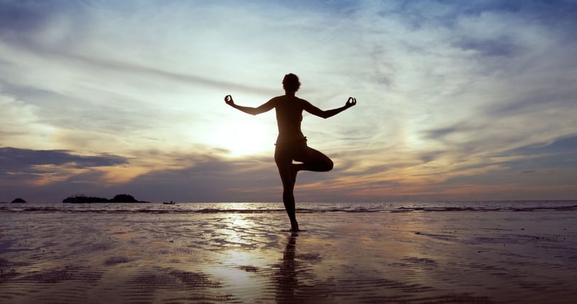 a woman doing yoga exercises on the beach