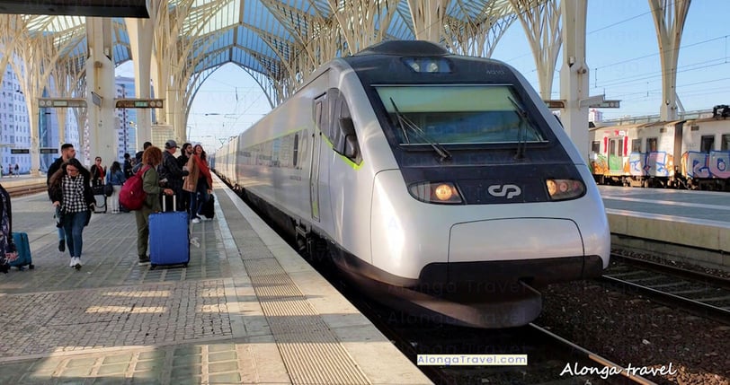 a train station with  people with suitcases & a train with the Comboios de Portugal logo on it