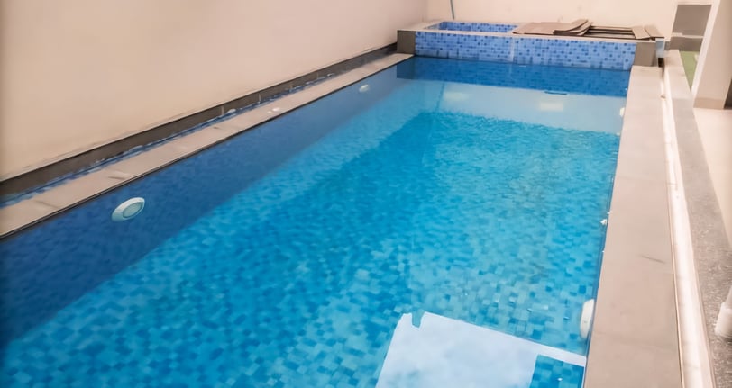 kolam renang minimalis di halaman belakang dengan finishing keramik roman berwarna biru