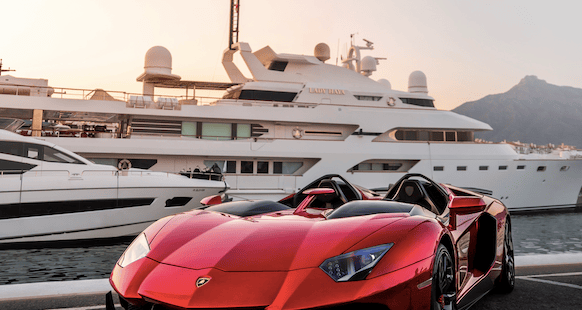 a red sports car parked in front of a yacht