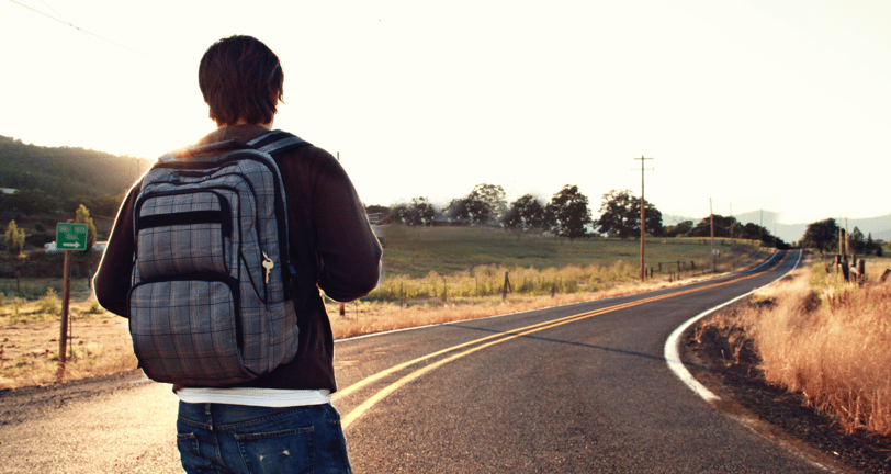 Ein alleinreisender Mann mit Rucksack auf einer Straße