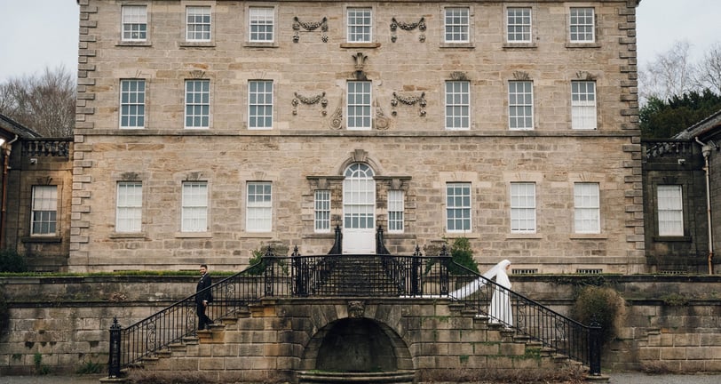 a large stone building with a staircase leading with bride and groom