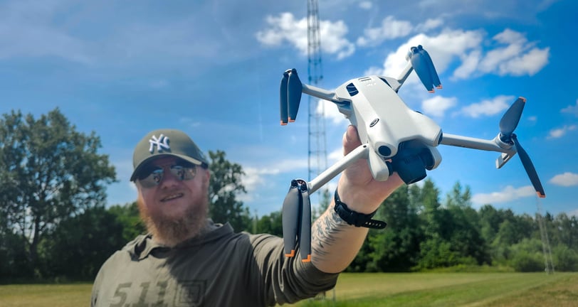 Dronepiloot toont DJI Mini 4 Pro drone in open veld tijdens voorbereidingen voor luchtinspectie op locatie