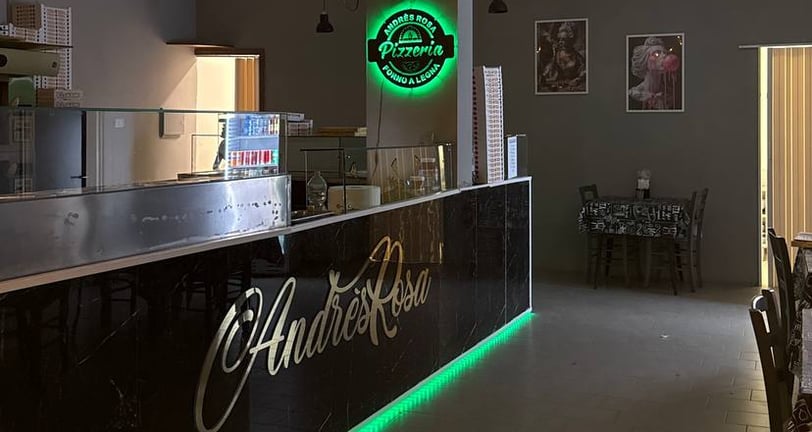 Bancone interno di AndrèsRosa Pizzeria ad Alseno con il logo visibile, ambiente accogliente e modern