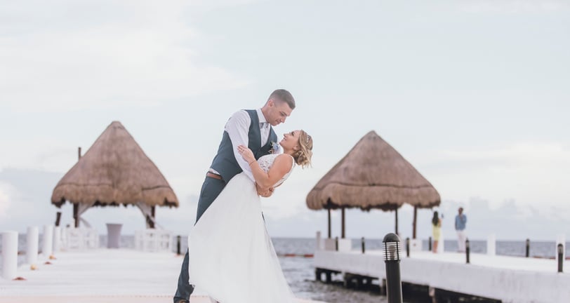 a bride and groom kissing on a pier