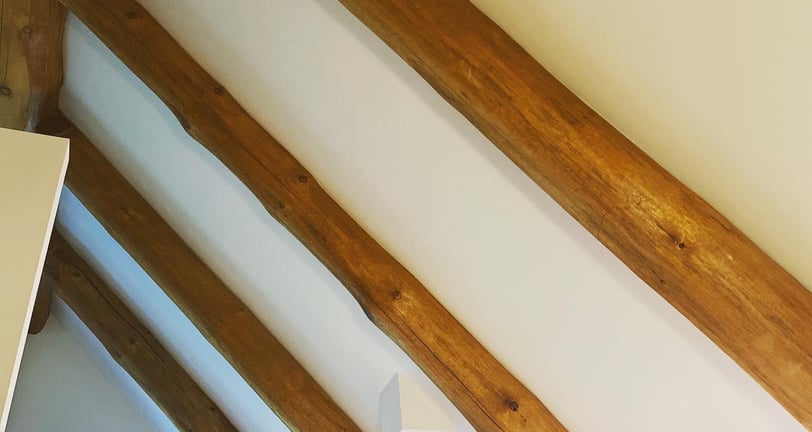 Finished drywall ceiling with exposed log beams