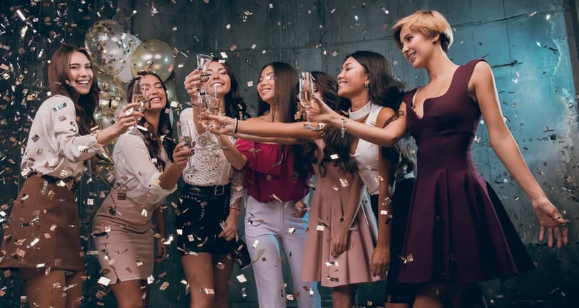 Women toasting with champagne surrounded by falling confetti on Fremont Street.