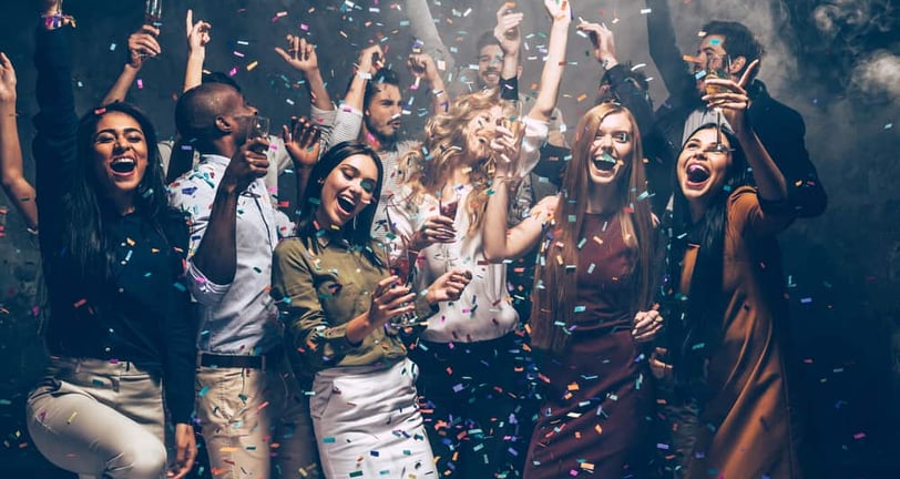 Group of friends celebrating under confetti at a Fremont Street party in Downtown Las Vegas.