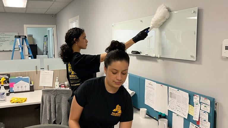 two women cleaning in a cubicle
