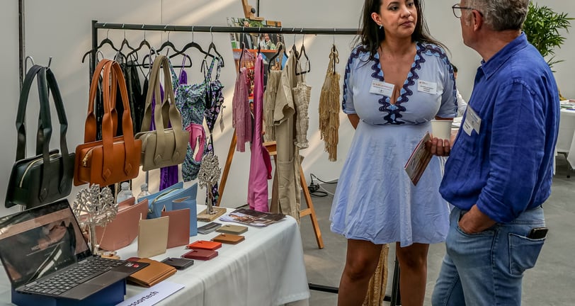 Un homme et une femme qui discute devant des articles de maroquinerie un stand qui vend