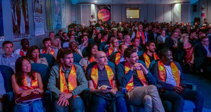 Les participants à la conférence sont assis dans la salle de spectacle et regardent la scène