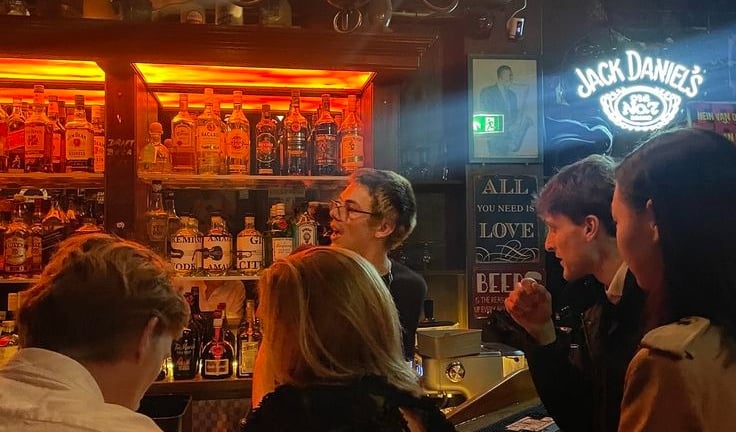 a group of people standing around a bar in Riga
