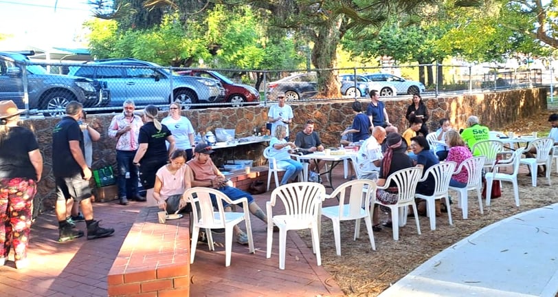 a group of people sitting at tables in a park