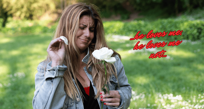 a woman in a denim jacket and plucking petals from a white rose
