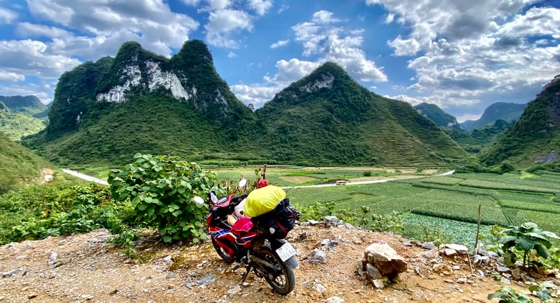 a motorcycle parked on a dirt road near a mountain in Vietnam