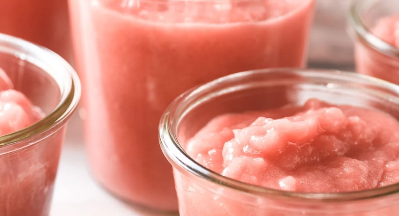 Clear jars containing pink rhubarb applesauce
