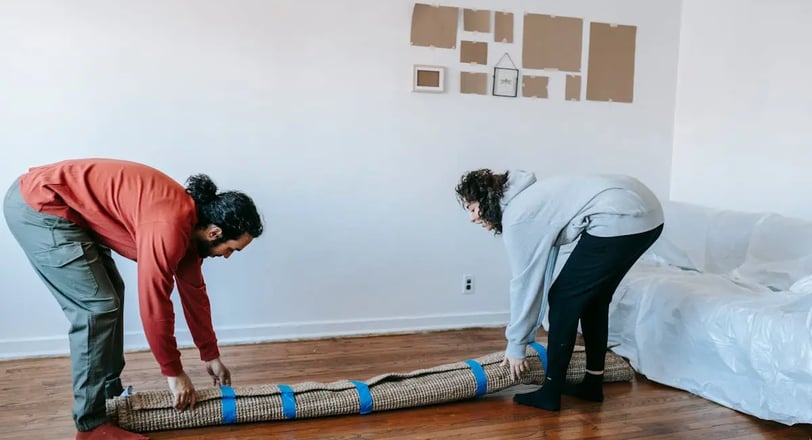 two people handling a packed rug
