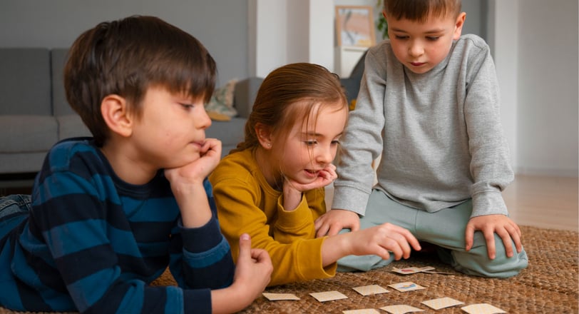 Crianças jogando um jogo de memória com cartas no chão