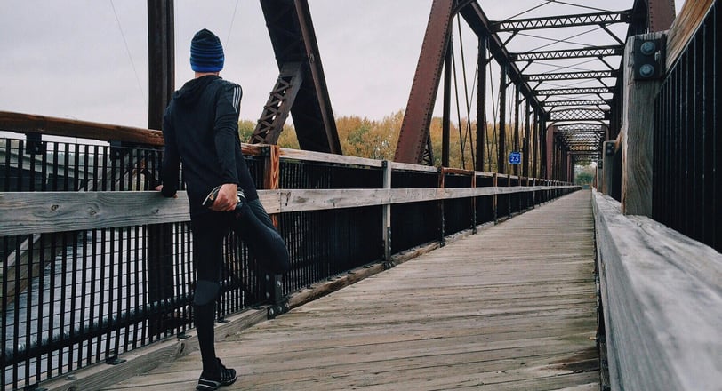 a man in a blue hat and a blue jacket is standing on a bridge