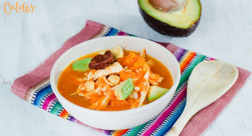 A chicken soup with chickpeas, avocado, and chipotle in a tomato-based broth