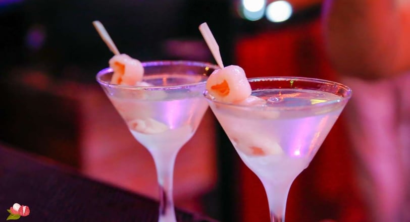 Luxurious Nobu-style lychee martinis, garnished with skewered lychees, glowing in a chic nightlife setting