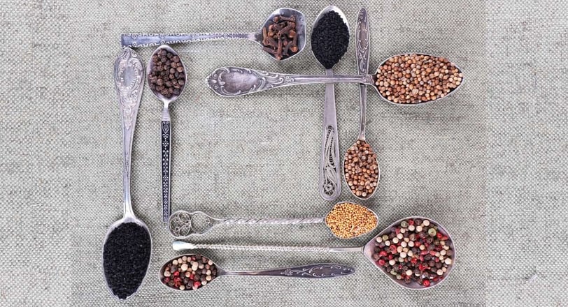 Comparison of teaspoon, dessert spoon, and tablespoon sizes on a wooden background