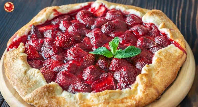 Rustic strawberry crostata with a golden-brown crust, filled with juicy strawberries and garnished with a sprig of mint