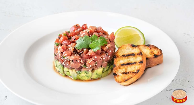 Tuna tartare topped with avocado slices and microgreens, served as a stylish and healthy appetizer option