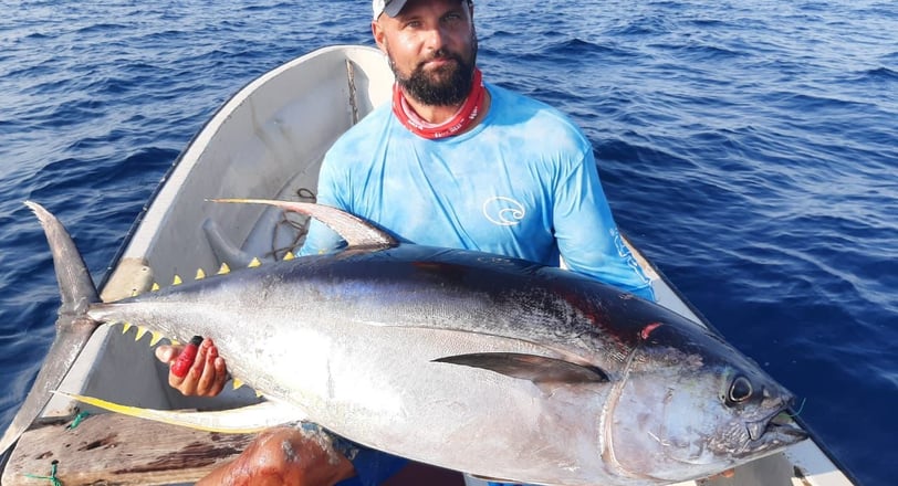 An angler proudly displaying a Tuna caught at one of the best fishing spots in Zanzibar, with a fi