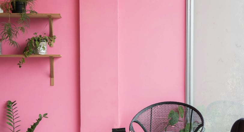 a pink room with a chair and a chair