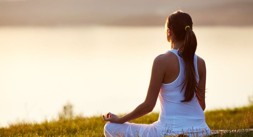 a woman sitting in a field meditating