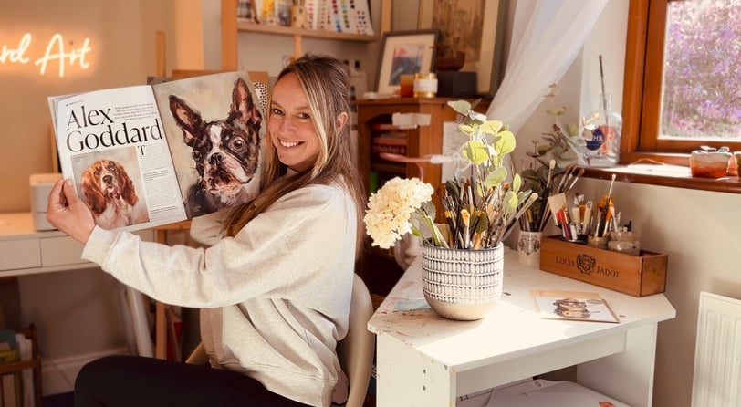 Alex Goddard in her studio with the magazine feature that she was featured in