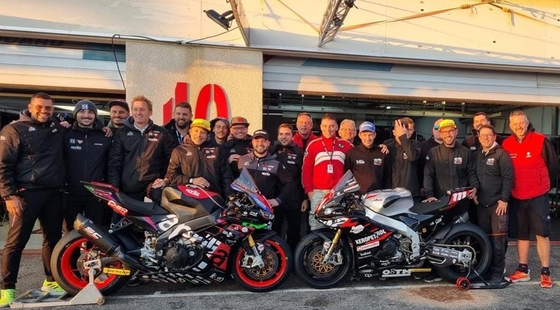 a motorcycle racing team standing around a motorcycle