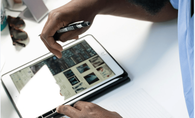 a man is holding a pen and writing on a tablet