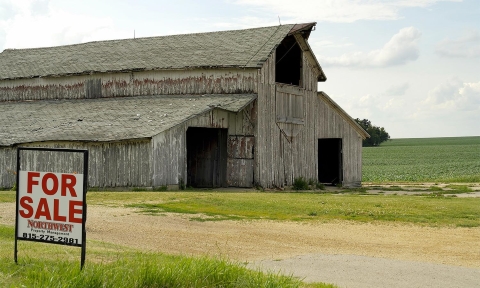 a barn with a for sale sign in front of a barn