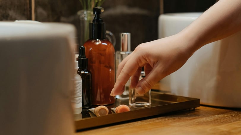 A person about to pick a cream or a serum out of several on a bathroom cabinet.