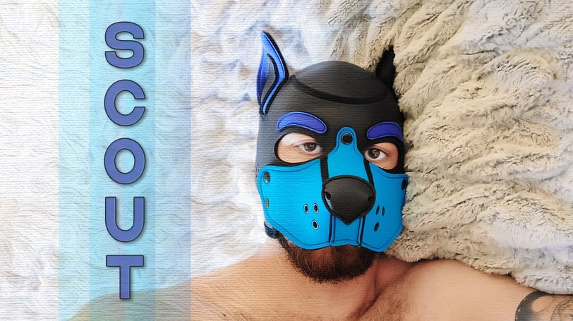 A man in a pup mask, with a name plate: SCOUT