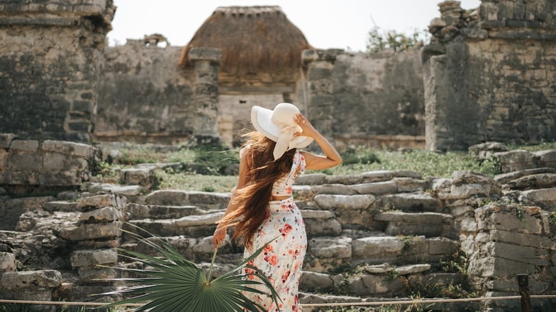 Back View o Woman in a Summer Outfit Looking at House of the Halach Uinic at Mayan Ruins in Tulum.