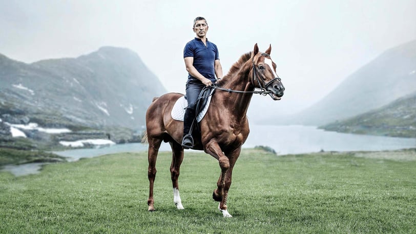 A rider on a horse in a mountain setting, embodying elegance and adventure for an equestrian brand.