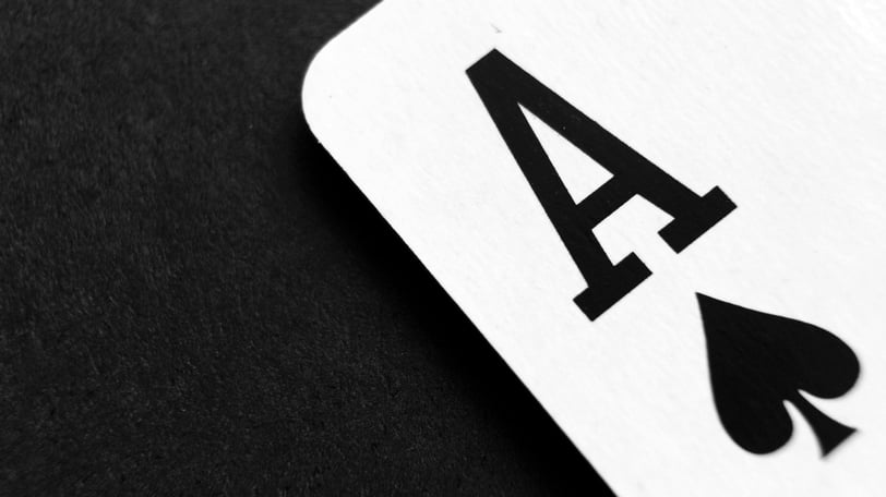 The corner of a playing card, the ace of spades, against a black fabric background.