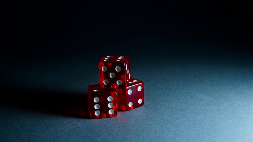 Three translucent red dice, stacked in a pyramid against a heavily shadowed backdrop.