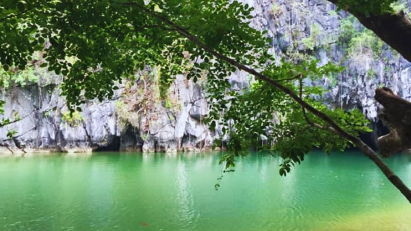 Vista da entrada da caverna com águas claras refletindo a luz.